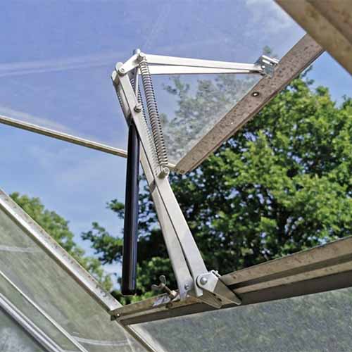 A close up square image of an automatic vent opener on a cold frame.