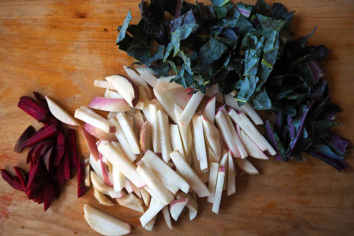 A close up top down horizontal image of chopped ingredients for preparing a ferment set on a wooden surface.